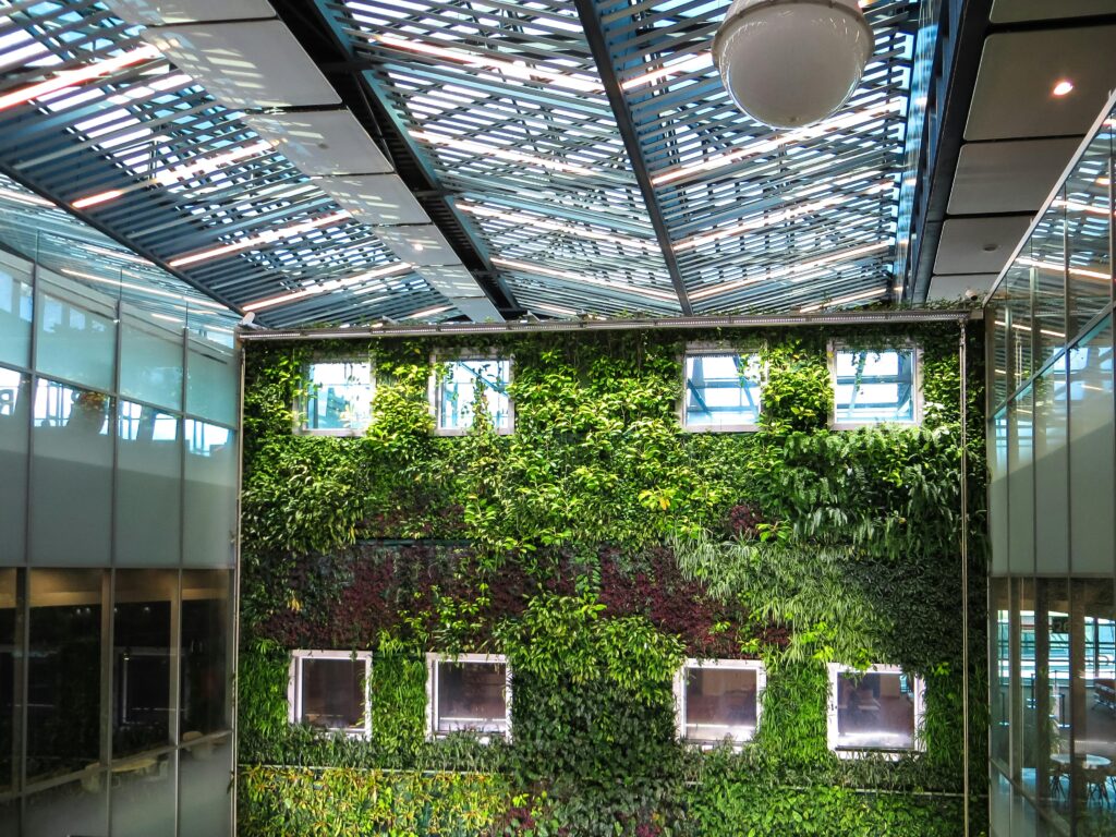 Contemporary indoor space featuring a lush vertical garden and a sleek glass roof, blending nature with architecture.